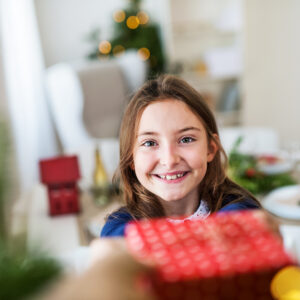 A small girl with a present at home at Christmas time. Presentes de Natal 2023